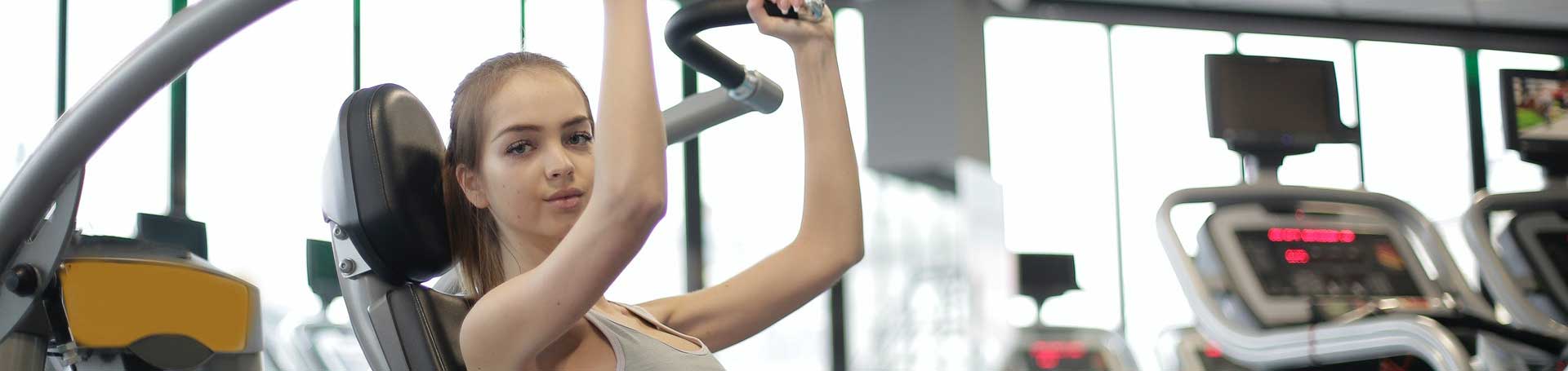 woman facing camera while using gym workout machine